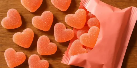 Dulces en forma de corazón, con un delicioso sabor a corazon de melocoton, esparcidos sobre una mesa de madera y saliendo de un paquete rosa.