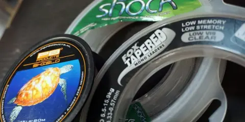Wybór między żyłką a plecionką to kluczowa decyzja wędkarza. Na zdjęciu widać różne rodzaje żyłek, w tym PB Products Shield i Fox Tapered Mono Leaders.