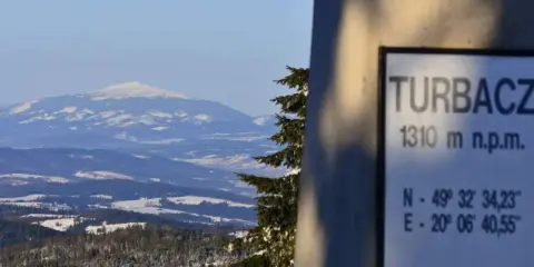 Zimowy krajobraz z Turbacza, szczytu o wysokości 1310 m n.p.m. Śnieg pokrywa okoliczne góry i lasy.
