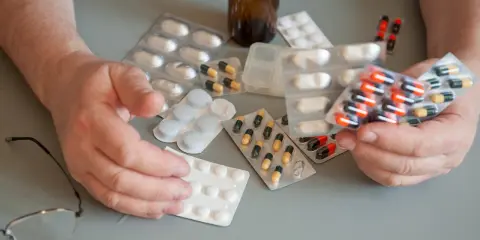 Ręce seniora trzymają opakowania z lekami. Czy leki dla seniorów są za darmo? Wiele osób zastanawia się nad tym pytaniem.