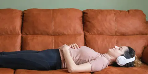 En elitidrottare vilar på en soffa med hörlurar, fokuserad på sin vilopuls.