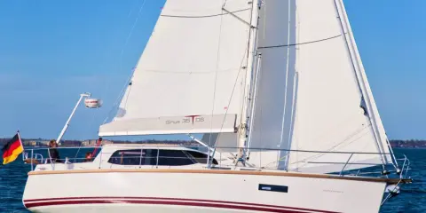Voilier blanc Sirius 35 DS naviguant sur une mer bleue, avec le drapeau allemand à l'avant.