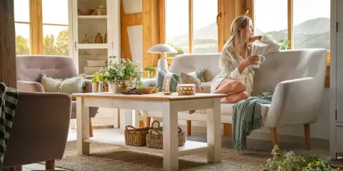 Przytulny salon w wiejskim stylu z kobietą pijącą kawę i podziwiającą widok.