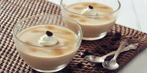 Deux verrines de crème au café façon Danette, garnies de chantilly et d'un grain de café.