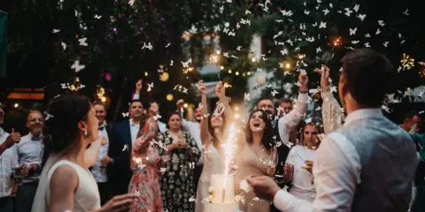 Fröhliche wedding party mit Funken sprühenden Wunderkerzen und flatternden Schmetterlingen aus Papier.