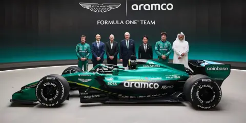 El equipo Aston Martin Aramco Cognizant Formula One Team posa junto a su coche verde brillante.