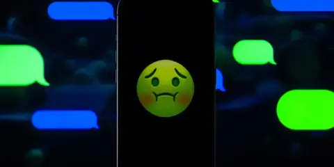 Smutna buźka na ekranie telefonu, otoczona zielonymi i niebieskimi dymkami czatu. Czy to znak, że nawet iMessage potrafi zasmucić?