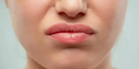 Gros plan sur une bouche pincée, le nez rouge que faire ? Une expression de dégoût ou de gêne.