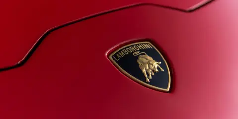 Złoty byk na czarnym tle z napisem "Lamborghini" - tak wygląda znaczek tej marki na czerwonej karoserii.