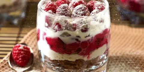 Pyszne desery w pucharkach z malinami i kremem, posypane cukrem pudrem. Idealne na letnie popołudnie.