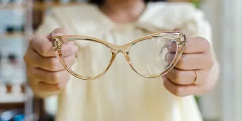 Osoba trzyma okulary korekcyjne, które pomagają widzieć wyraźniej.