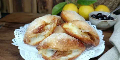 Monachine salentine dorate e zuccherate, un dolce profumato con ripieno di mele e un tocco di ciliegie.