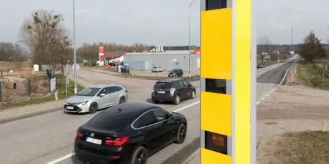 Żółty fotoradar przy drodze, monitorujący ruch samochodów. Tak działa system, który rejestruje prędkość pojazdów.