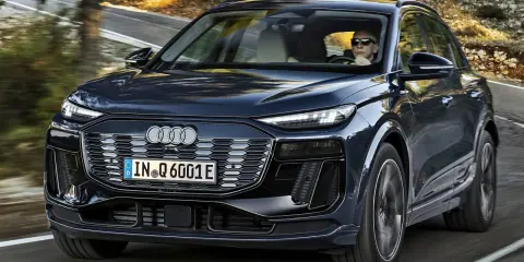 Ciemnogranatowy Audi Q6 e-tron jedzie po krętej drodze. Sprawdź atrakcyjną audi q6 e-tron cenę.