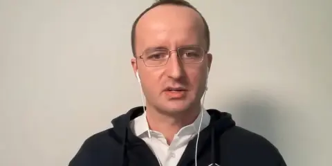Kris Marszalek, CEO Crypto.com, w okularach i słuchawkach, w czarnej bluzie z logo.