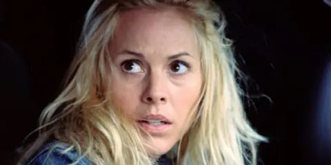 Przerażona kobieta z blond włosami, wpatrzona w coś poza kadrem. Ten moment z filmu sprawia, że widz czuje się jak bohater, oglądając mega wciągające filmy.