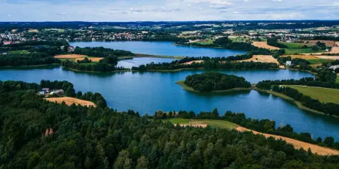 Krajobraz Kaszub z jeziorami, lasami i polami uprawnymi pod błękitnym niebem.