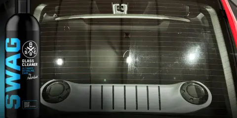 Butelka czyściwa SWAG Glass Cleaner obok tylnej szyby samochodu. Idealne do utrzymania czystości.