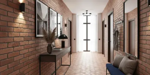 Korytarz z ceglanymi ścianami i podłogą w jodełkę. Wnętrze zdobią czarne lamele, obrazy i nowoczesne oświetlenie.