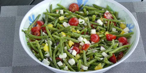 Salade estivale de haricots verts, tomates cerises, poivrons jaunes et feta. Un délice frais et coloré.
