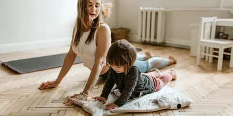 Mama i dziecko ćwiczą jogę. To świetne gry i zabawy ruchowe przykłady dla całej rodziny.