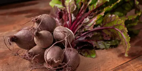 Un bouquet de betteraves fraîches, prêtes pour une délicieuse recette betterave. Leurs feuilles vertes et leurs racines pourpres promettent saveur et couleur.