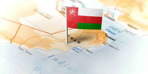 Flaga Omanu wbita w mapę, wskazująca gdzie leży Oman, nad Zatoką Omańską, w pobliżu Maskatu.