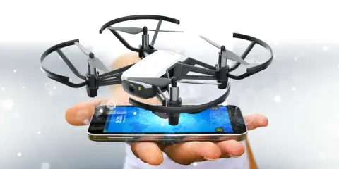 Kleine Drohne schwebt über einem Smartphone, das die tello app anzeigt.