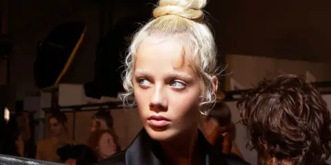 Ein Model mit einem eleganten Dutt und zarten Babyhaaren, die um das Gesicht fallen.