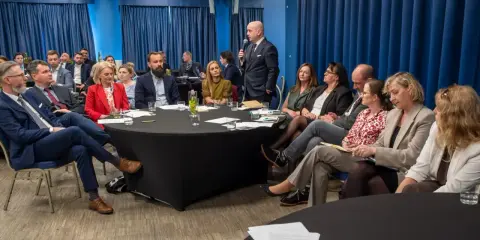 Grupa prawników siedzi przy okrągłych stołach podczas konferencji w Krakowie.