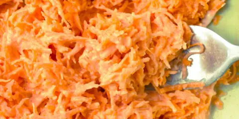 Pyszna surówka z marchewki jak z restauracji, kremowa i apetyczna. Widok z bliska na starte marchewki z sosem.