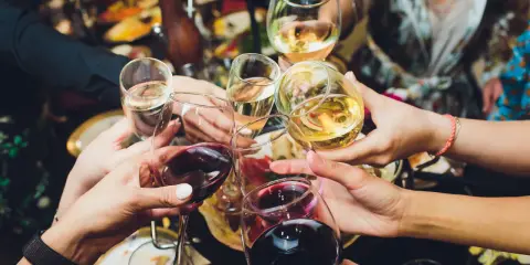 Ręce wznoszą kieliszki z winem, białe i czerwone, do toastu. Rozpoczyna się radosne świętowanie i trawienie alkoholu.