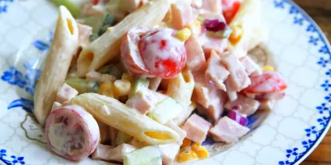 En krämig pastasallad med kassler, penne, körsbärstomater, gurka och majs. Perfekt för en snabb och god lunch.