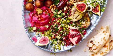 Bunte Mezze-Platte mit Hummus, Falafel, Granatapfel, Feigen und Fladenbrot. Perfekt für ein köstliches Abendessen.