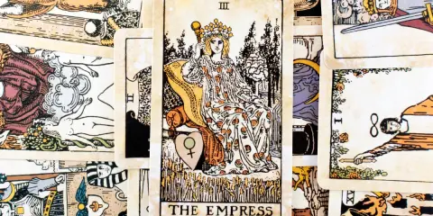 Karta Tarota "The Empress" z koroną i berłem, siedząca na tronie, otoczona innymi kartami.