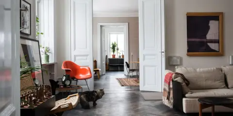 Erika Kangas hem med en katt som smyger förbi en orange stol och en soffa.