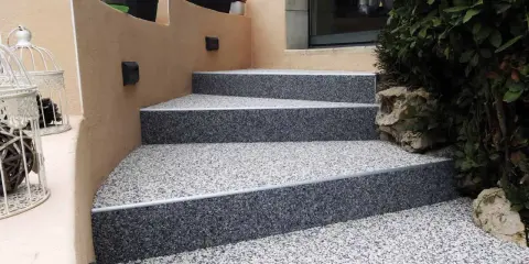 Escalier extérieur avec revêtement de sol en gravier coloré, un aménagement extérieur moderne et résistant.