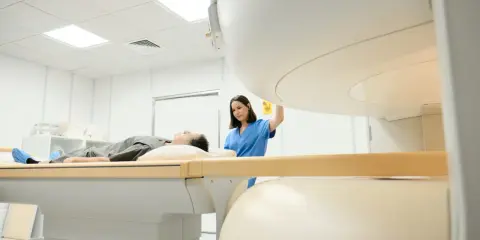 Pacjent leży na stole do rezonansu magnetycznego, pielęgniarka przygotowuje badanie. Rezonans barku interpretacja jest kluczowa dla diagnozy.