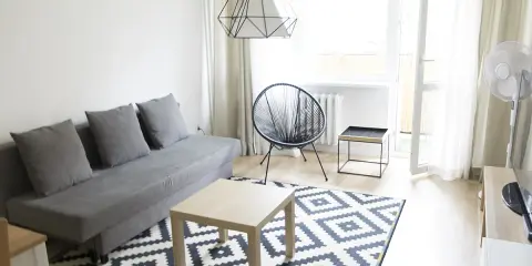 Nowoczesny salon z szarą kanapą i geometrycznym dywanem. Stylowa metamorfoza pokoju tanim kosztem.