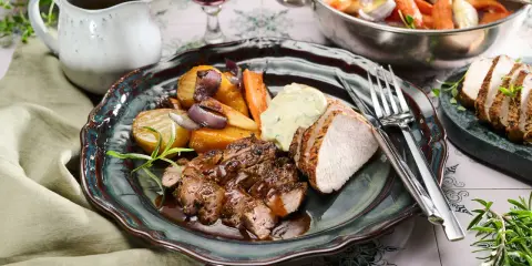 En tallrik med saftig fläskfilé, rostade rotfrukter och en klick örtsås. En härlig middag i svartvitt.