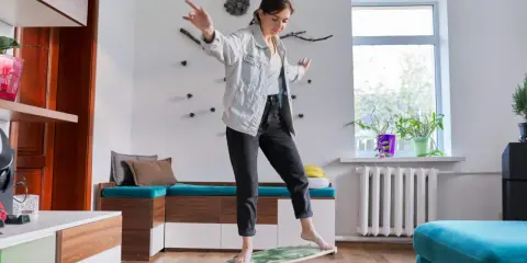 Kvinna balanserar på en balansbräda, en övning som kan hjälpa till med fokus och inre lugn, liknande en hjärtchakra meditation.