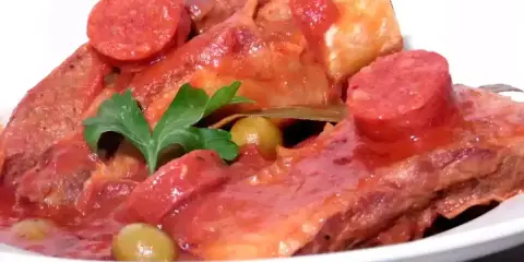 Plats de poitrine de veau mijotée, garnie de rondelles de chorizo, d'olives vertes et d'une feuille de laurier. Une recette savoureuse.
