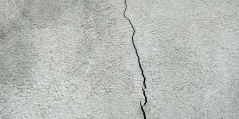 En spricka löper genom ett gråspräckligt putsbruk.