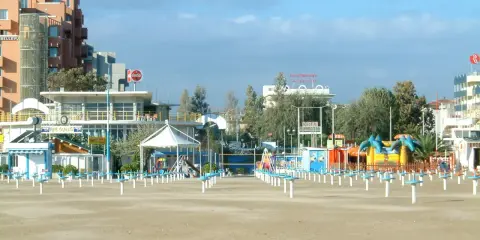 Spiaggia di Rimini a settembre, con ombrelloni chiusi e giochi per bambini in attesa della prossima stagione.