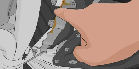 Dedo señala una fuga de aceite en la parte inferior del motor. Mi coche pierde aceite por debajo.