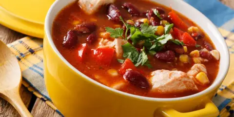 Aksamitna zupa meksykańska z kurczakiem, fasolą, kukurydzą i papryką, udekorowana natką pietruszki.