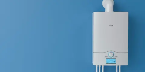 Nowy, biały piec gazowy na niebieskiej ścianie. Dowiedz się, jak wyłączyć piec gazowy na lato, aby oszczędzać energię.