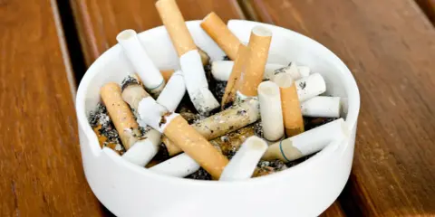 A full Aschenbecher mit Zigarettenstummeln. Vielleicht ein Hinweis auf die Champix-Nebenwirkungen, die das Rauchen erschweren.
