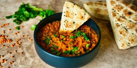 Herzhafte Linsenrezepte: Ein dampfender Linseneintopf mit frischer Petersilie und Fladenbrot.