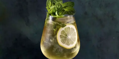 Un verre de Hugo Spritz rafraîchissant, garni de menthe fraîche et d'une tranche de citron. Parfait pour une recette d'été.